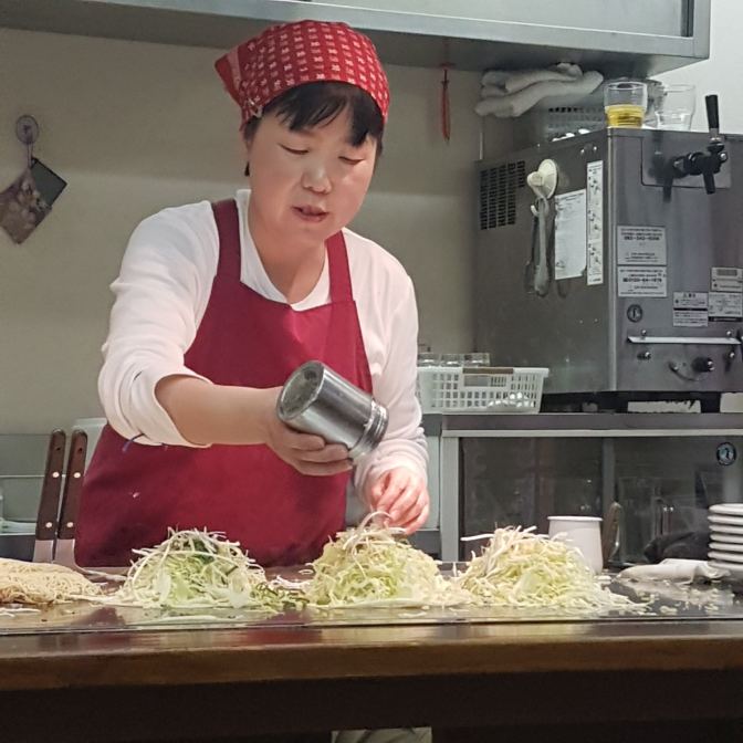 Okonomiyaki wordt gemaakt op een gloeiende plaat